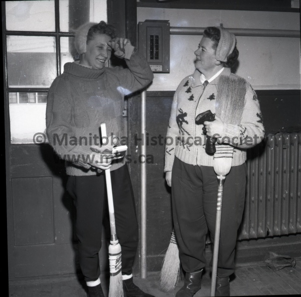 (Tashiro) February 26 - 1960 (Sports)
56 Rinks Entered In Portage Ladies Bonspiel
Boy, was that close! Mrs. Gwen Delf of Rathwell wipes a fevered brow after turning back a courageous comeback by the Macdonald rink of Pine Falls. Mrs. Delf had a seven-up lead early but had to make a good shot on the last end to triumph. Mrs. Edith Vandell, third on the Delf rink, seems to be taking victory in stride.
Dale Macdonald. a top-notch curler himself, is relegated to the sidelines with a vengeance. Dale, here, babysits with his two young daughters while Mrs. Macdonald does battle in the Portage ladies bonspiel. The betting is that Dale, by Thursday night, will be happy to see the last of this year's edition of the 'spiel.
Dignitaries taking part in the opening ceremonies of the Portage ladies curling club bonspiel, held between draws Monday afternoon, were, left to right, Mrs. Ann Hutchinson, president of the ladies curling club; Mrs. H. L. Henderson, wife of Mayor Henderson, and Max Wilton, president of the Portage curling club.
Mrs. Jean Farncombe of High Bluff doesn't seem to mind attending to the distasteful side of the Portage ladies' bonspiel - that's payment of fees, naturally. Here she is shown registering her rink and paying her fees to Mrs. Helen Wishart as the big 'spiel got under way Monday morning. 6916d.jpg